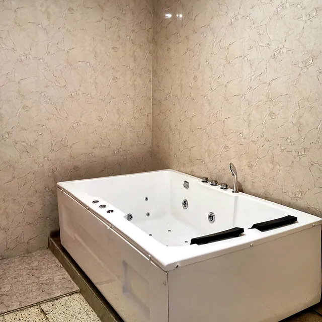 Two-person jacuzzi bathtub in a marble-tiled room
